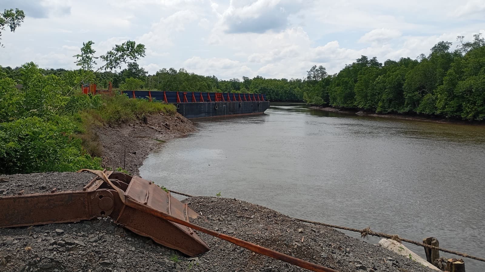 Tongkang bersandar di jetty pada alur sungai.
