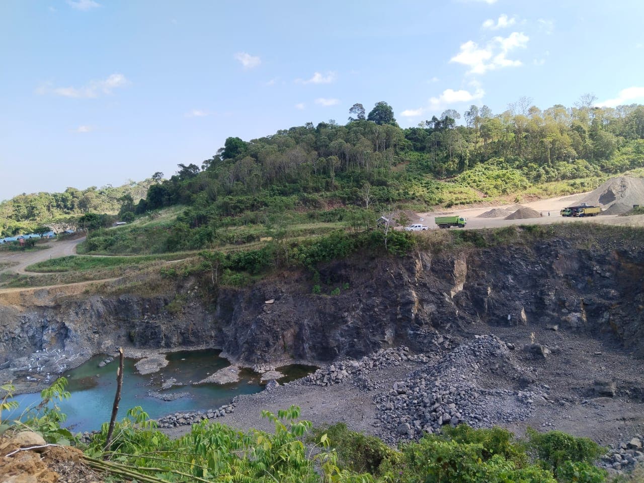 Dinding tambang dengan genangan air di dasar pit.